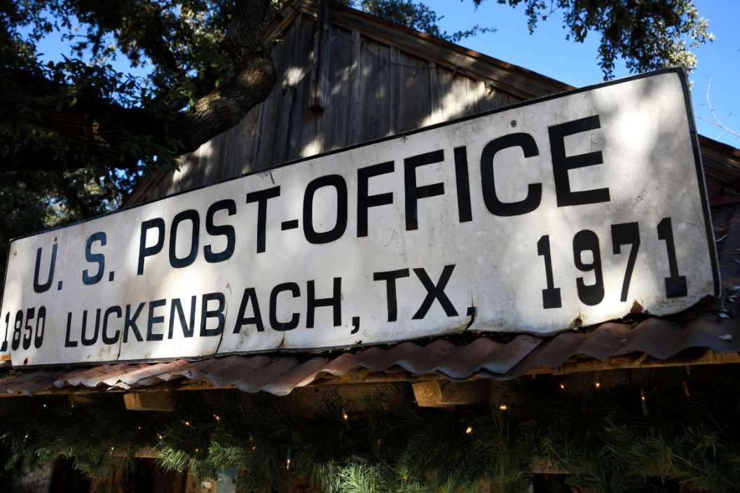 A sign identifies a building which served as a U.S. post office between 1850 and 1971 before it and surrounding land was coverted into a general store, bar and venue for live country music. Luckenbach, Texas, is an unincorporated community and tourist attraction near Fredericksburg in the Texas Hill Country.