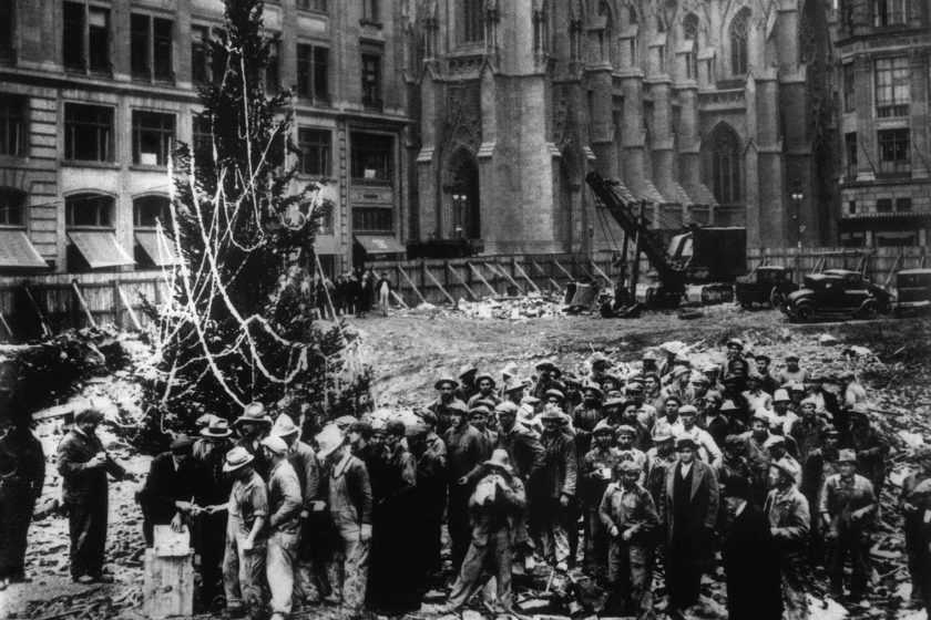 ** FILE ** Construction workers line up for pay beside the first Rockefeller Center Christmas tree in New York in this 1931 file photo. The Christmas tree went on to become an annual tradition and a New York landmark. St. Patrick's Cathedral is visible in the background on Fifth Avenue.