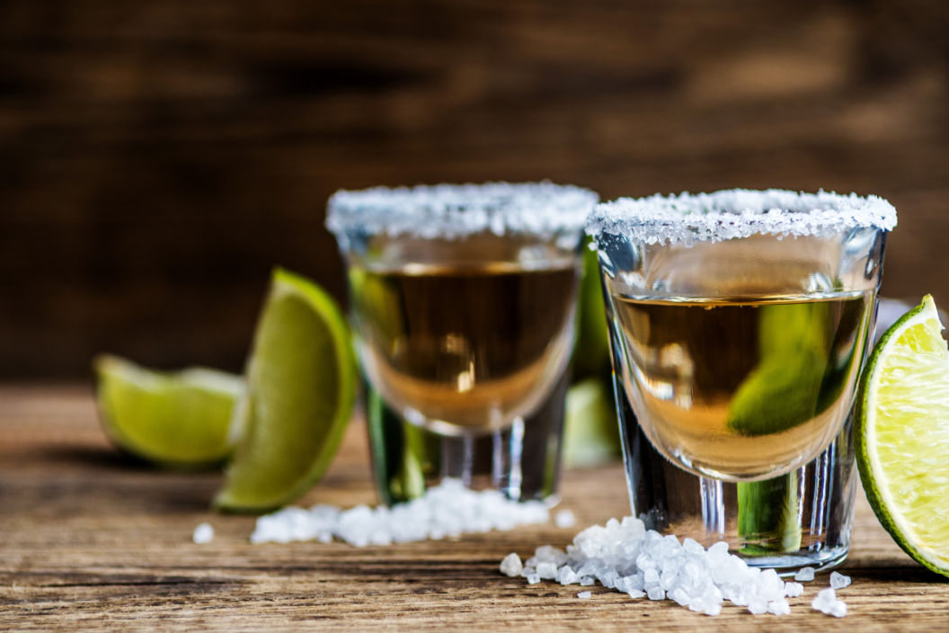 Tequila with lime and salt and ice cube on wood table