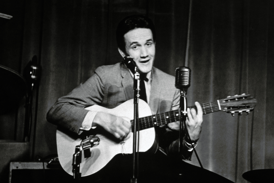 American country singer, songwriter and musician Roger Miller (1936 - 1992) playing the guitar on stage, 1960s.