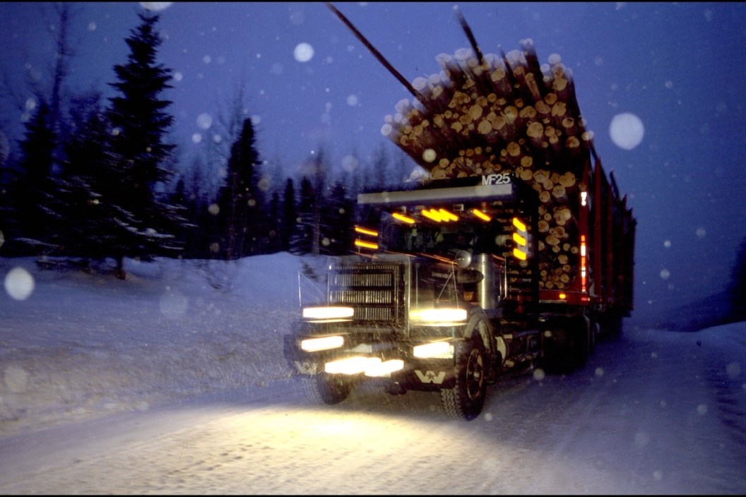 CANADA - JANUARY 01: Truck "Hors Route", Transport Of Wood, Saguenay, In Quebec, Canada In 2000-Day or night, nothing can stop the continual ballet of these truckers fear, not the same violent snowstorms. However, many drivers prefer to drive at night, the headlights of the truck all the more revealing pitfalls of frozen tracks. At 70 km / h, the 26 tires raise the snow from the runway. If there is no wind, visibility may be reduced to 1 km behind the truck. (Truck "Off Road", planetary type, total weight 150 to 170 tons). --- Night and day nothing can stop the rotations, not even the most violent storms.