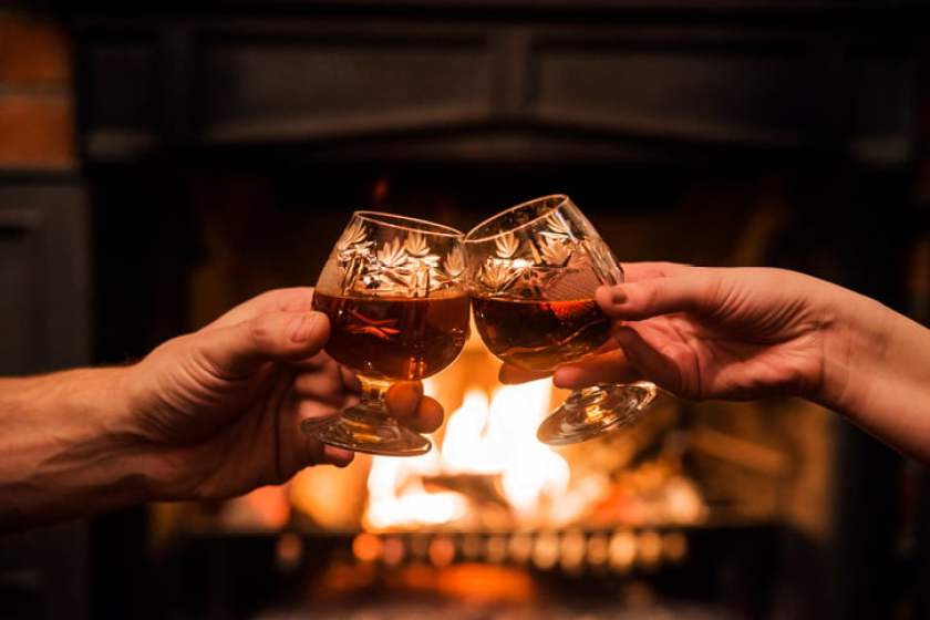 Couple with Two glasses of alcoholic drink in front fireplace