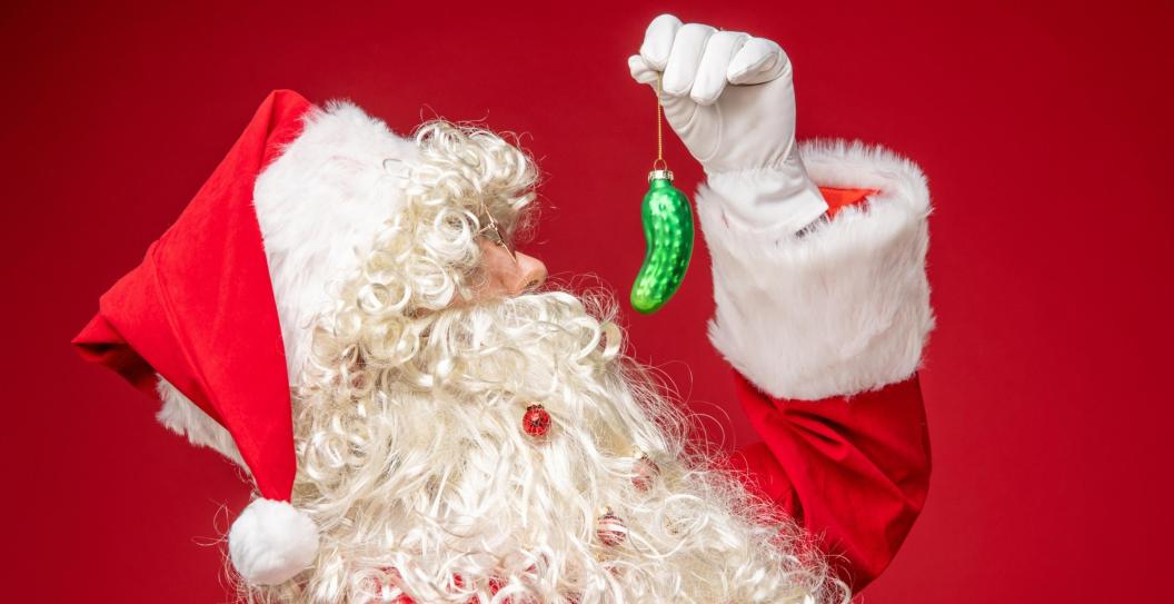 Santa Clause holding a Christmas pickle ornament