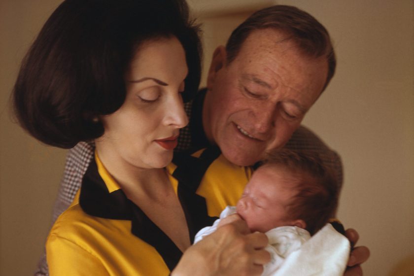 (Original Caption) Newport Beach, California: Actor John Wayne nuzzles up to his new baby, Marisa Carmela, at Wayne's home here March 12. Helping to hold the baby is the proud mother, Pilar, who gave birth to the young Wayne on February 22nd. Wayne just finished Eldorado for Paramount and will spend some time with his wife and daughter.