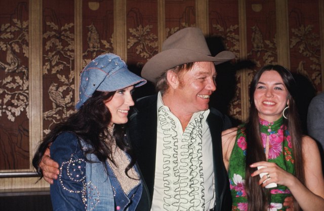 CIRCA 1976: Country singers and sisters Loretta Lynn (on left) and Crystal Gayle flank Loretta's husband Mooney Lynn at a soiree in circa 1976.