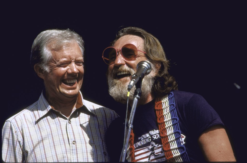 Former US Pres. James E. Carter Jr. (L) smiling broadly and standing next to Country and Western singer Willie Nelson (R) at concert during the town's 100th anniversary. (Photo by Thomas S. England/Getty Images)