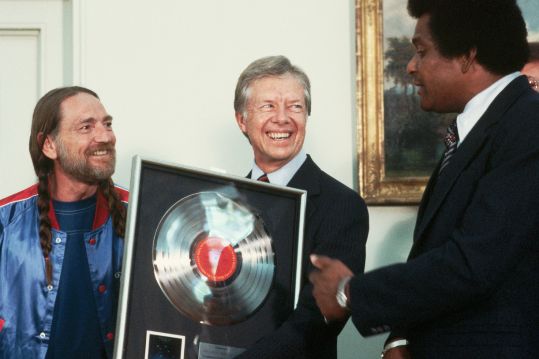 Country singers Willie Nelson and Charley Pride present a gold record to President Jimmy Carter at the Oval Office. (Photo by © Wally McNamee/CORBIS/Corbis via Getty Images)