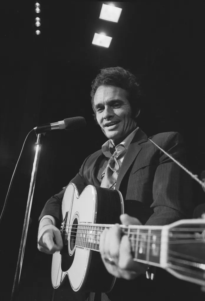 American country music performer Merle Haggard smiles as he plays an acoustic guitar, 1970. 