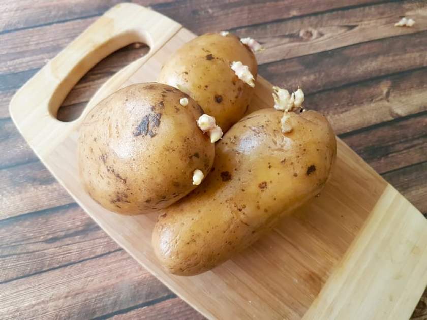 sprouted potatoes, wooden cutting board