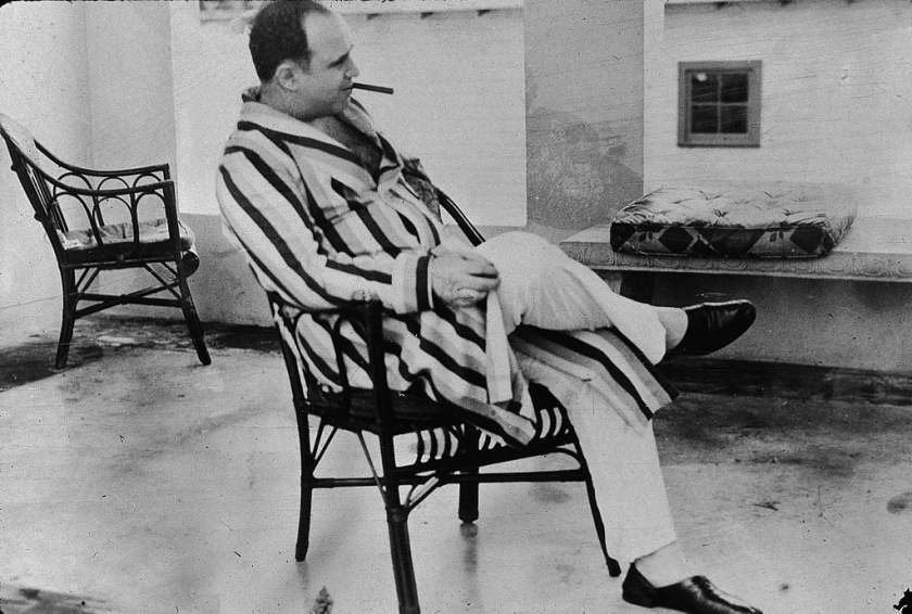 Capone smokes a cigar and wears a striped dressing gown and slippers. (Photo by New York Tim