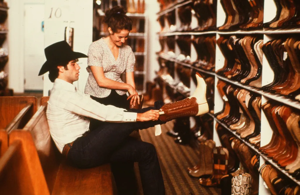 Actor John Travolta tries on cowboys boots in a scene during the Paramount Pictures movie  'Urban Cowboy" circa 1980. (Photo by Hulton Archive/Getty Images
