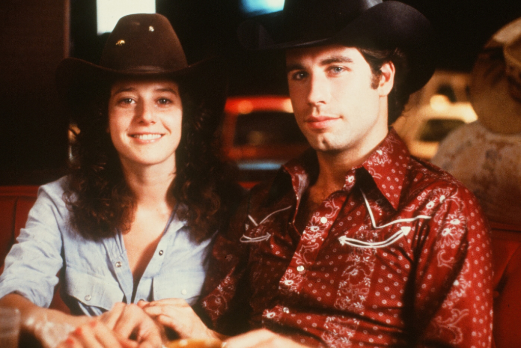 Actor John Travolta and Debra Winger smile on set of the Paramount Pictures movie 'Urban Cowboy" circa 1980.