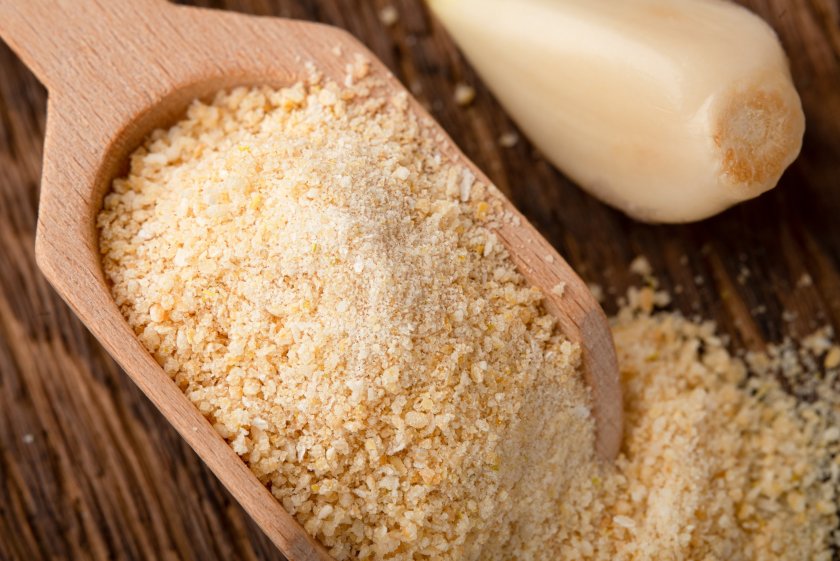 Top view granular garlic in a wooden scoop close up