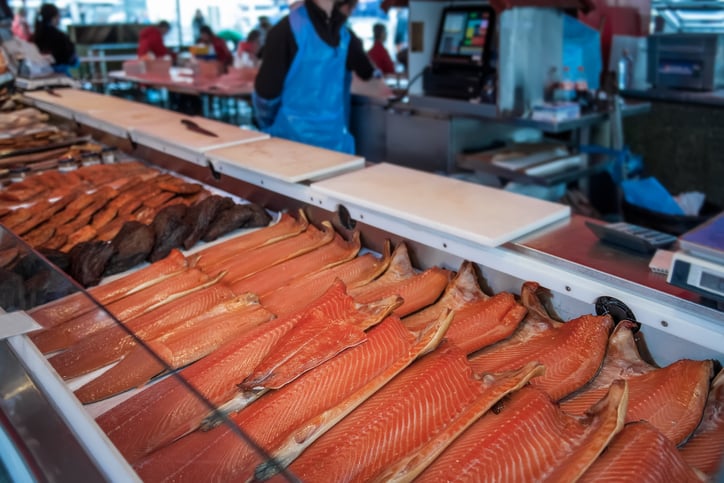 Large showcase with halves of delicious fish of the North sea trout, salmon, pink salmon on the counter in the Norwegian fish market. Close up.