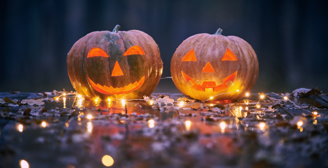 Two smiling Halloween Pumpkins on a wooden table with lights In A Mystic Forest At Night.