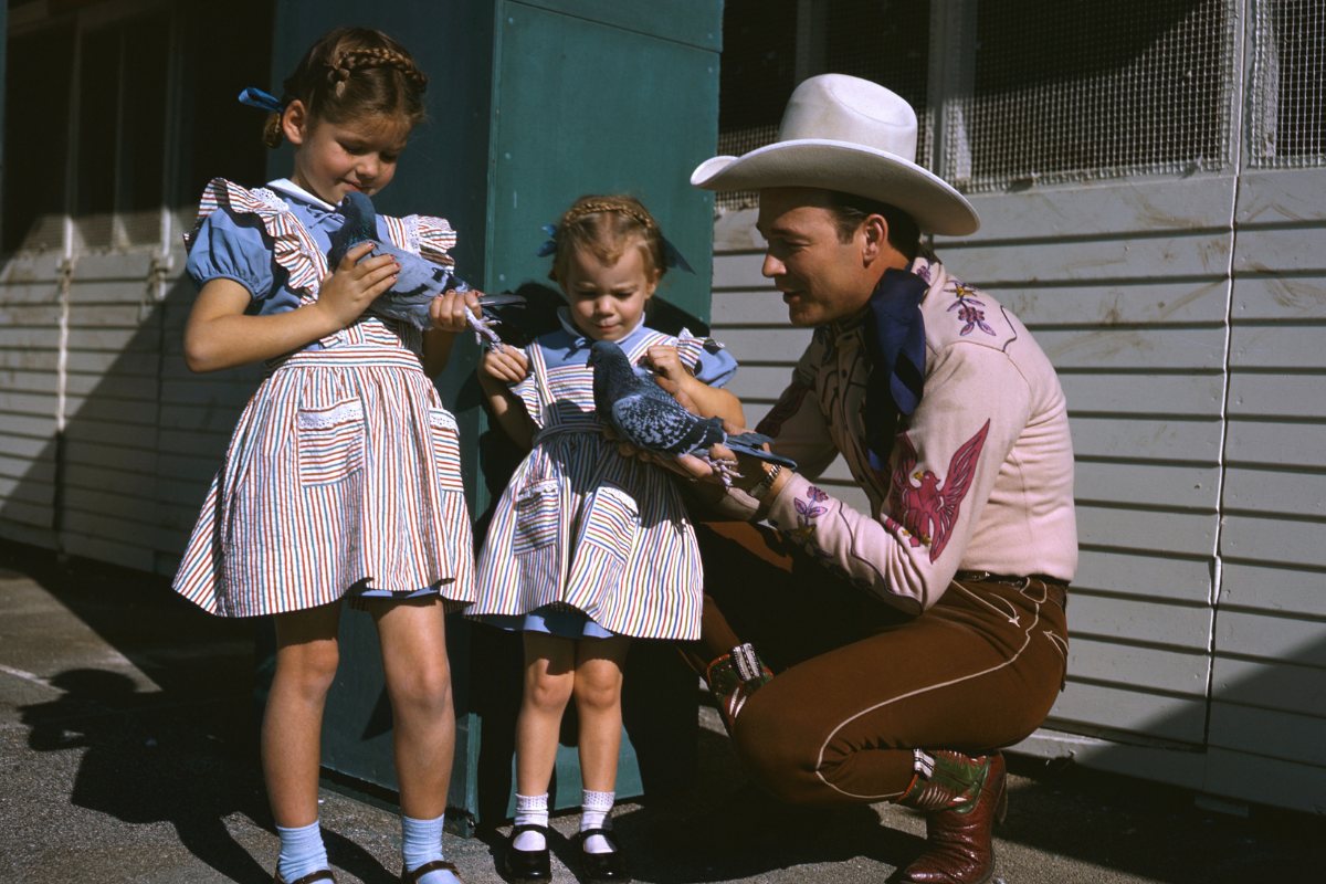 American actor Roy Rogers (1911 - 1998), a famous pigeon fancier, shares his hobby with his daughters Cheryl (left) and Linda Lou, circa 1946.