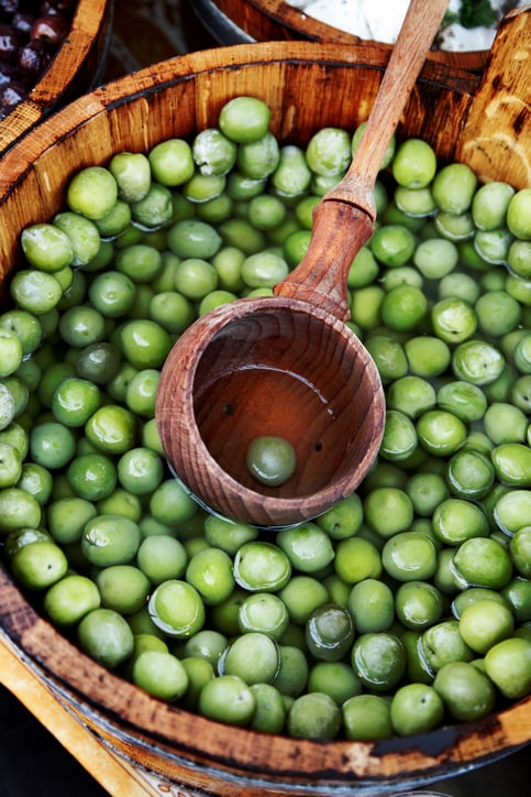 Large wooden barrel of green olives in brine.