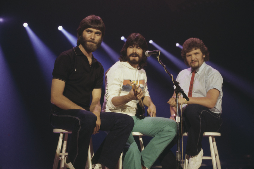 Alabama (Randy Owen, Teddy Gentry and Jeff Cook), U.S. country music band, pose sitting on stools, circa 1980.