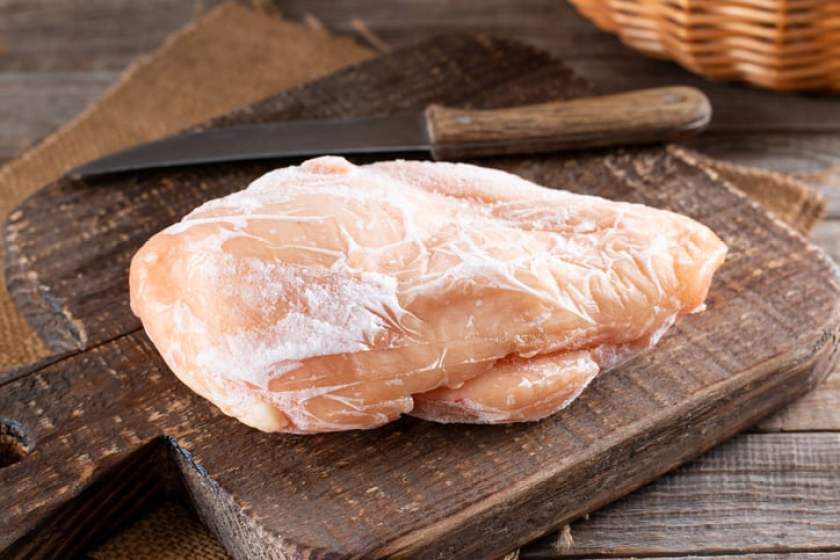 Frozen chicken fillet on a cutting board on a table. Frozen food