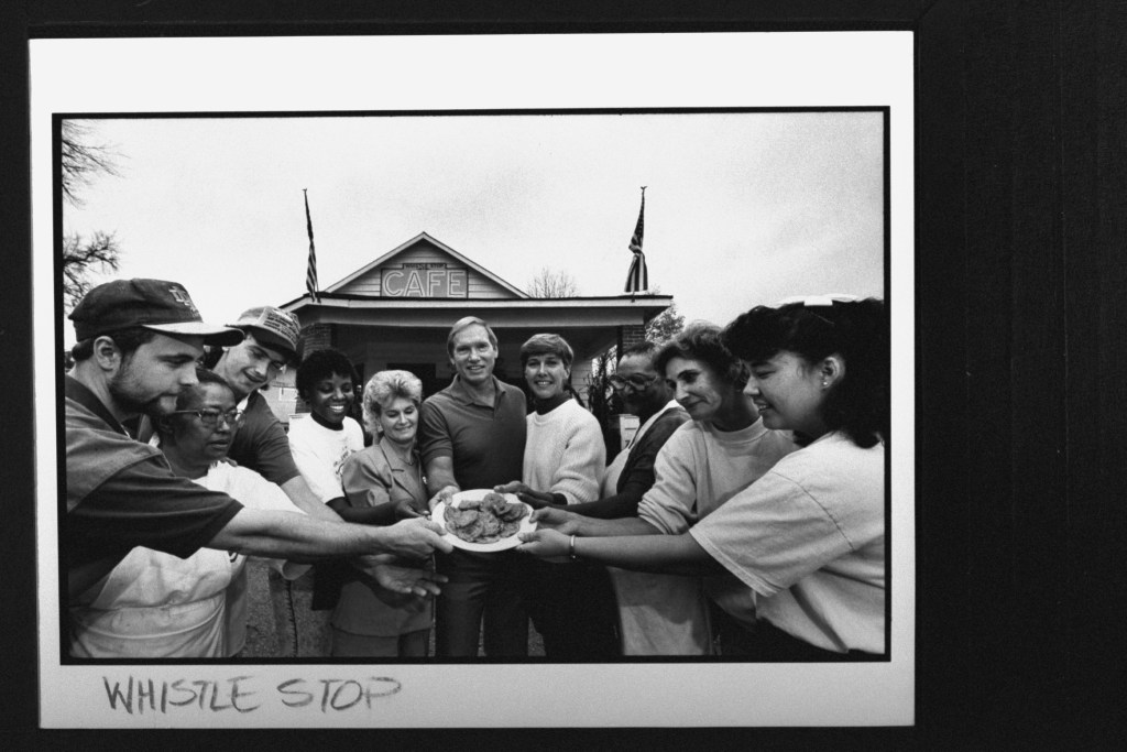 Restaurateurs Jerie Lynn and Robert Williams (4R and 5R) and their staff holding plate of fried green tomatoes in front of their restaurant, the Whistle Stop Cafe; the cafe was built for the film Fried Green Tomatoes; they bought and began operating th.e cafe after filming  