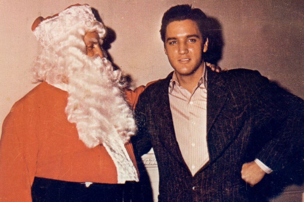 CIRCA 1965: Rock and roll singer Elvis Presley poses with Colonel Tom Parker (dressed as Santa Claus)in this Christmas card circa 1965.