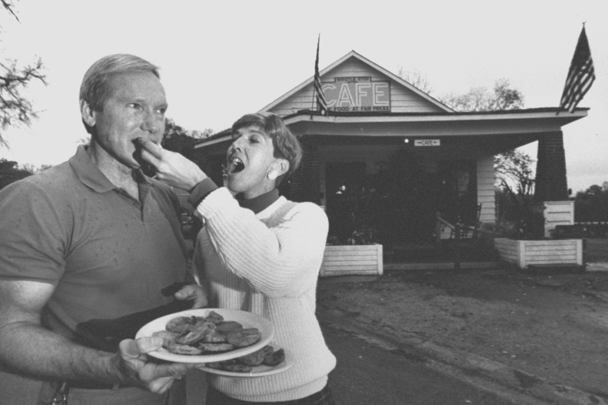 Restaurateur Jerie Lynn Williams feeding piece of fried green tomato to husband Robert in front of their restaurant, the Whistle Stop Cafe; the cafe was built for the film Fried Green Tomatoes; Robert & Jerie Lynn bought & began operating the cafe shor.tly after filming ended (Photo by Will And Deni McIntyre/Getty Images)