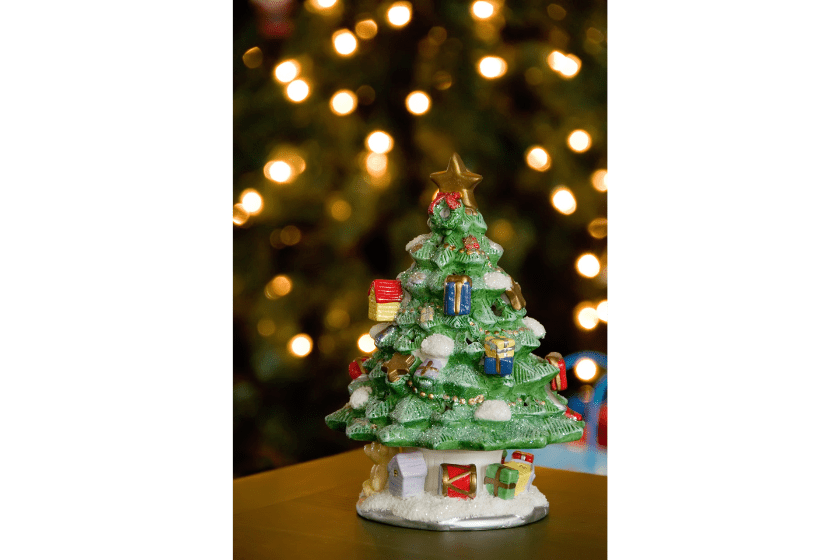 A Ceramic Christmas Tree in front of a real one blurred by depth of field.