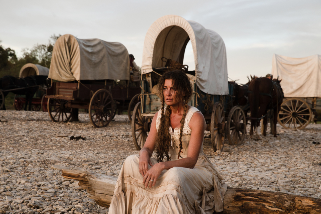 Margaret Dutton sits next to her covered wagon in '1883'