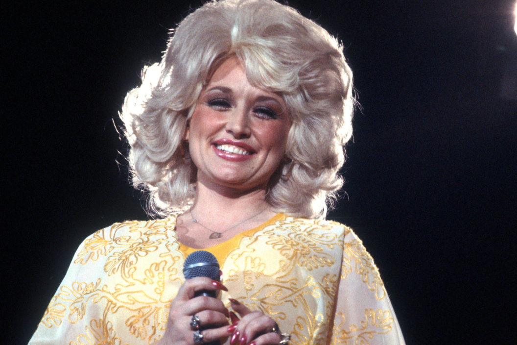 Country singer Dolly Parton performs onstage wearing a yellow dress, circa 1975, Los Angeles, California.