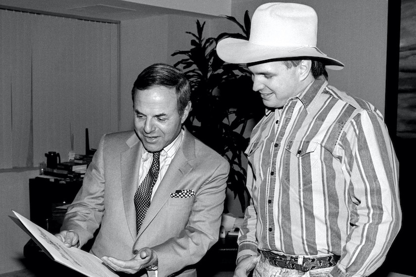 American music industry executive Joe Smith shows an award to American singer and songwriter Garth Brooks from the Mayor of Los Angeles Tom Bradley (not pictured) circa December, 1990 in Los Angeles, California. 