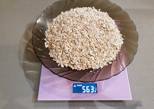 A plate of raw oatmeal stands on an electronic scale to measure the weight for cooking