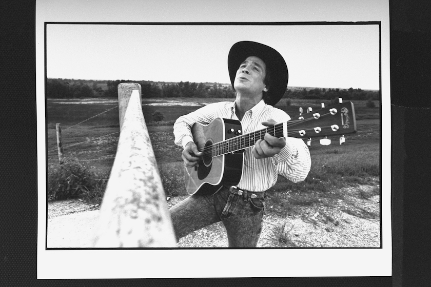 C & W star Clint Black singing w. guitar in field by fence near Freedom Fest concert.