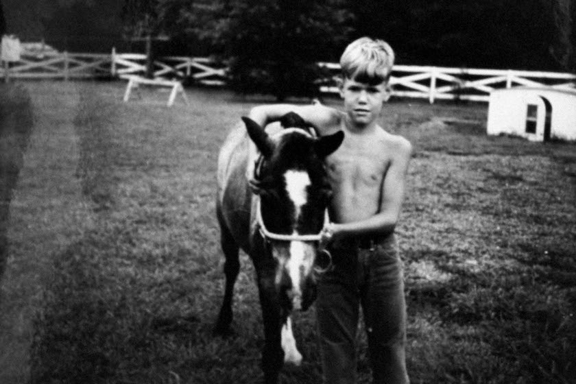 Snapshot of singer Randy Travis at age 10 with his arm around his pony Buckshot on farm.