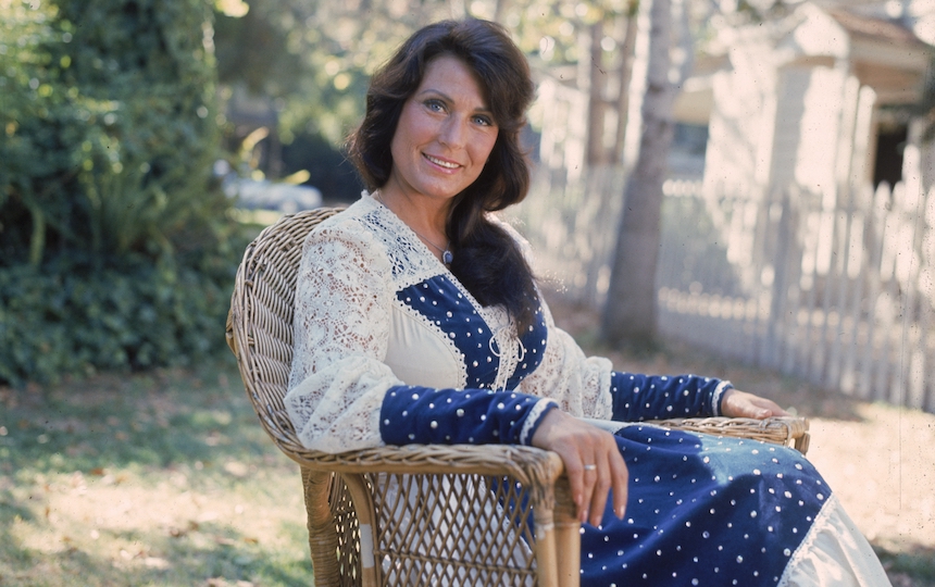 A 1978 portrait of American country music singer and musician Loretta Lynn sitting outdoors in a lace dress.