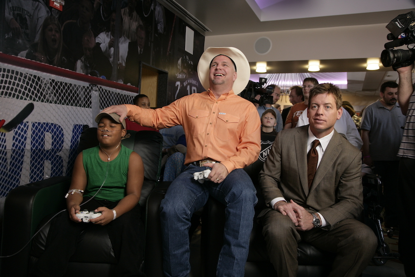Rodnick Phillips (L), a patient at Cook Children's Medical Center plays a video game with former American football quarterback Troy Aikman (R) and Country Singer Garth Brooks at the Cook Children's Medical Center January 15, 2008 in Fort Worth, Texas. Aikman and Brooks were present for the opening of the Zone, a new therapeutic play room at Cook Children's Medical Center which was funded in part by The Troy Aikman Foundation. 