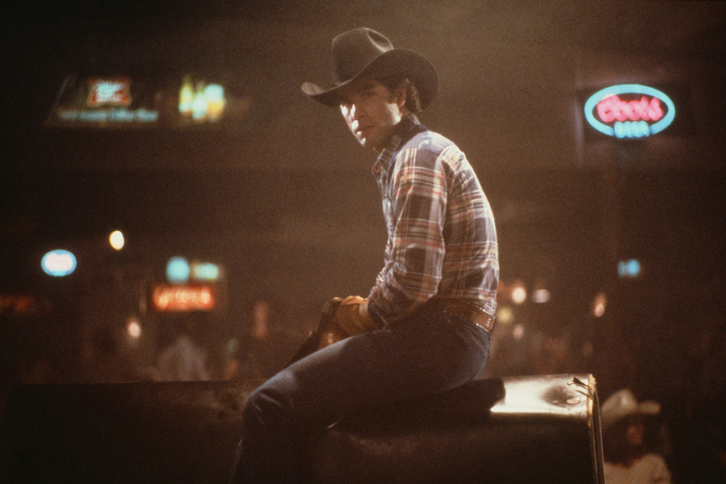 Actor John Travolta rides a mechanical bull in a scene during the Paramount Pictures movie 'Urban Cowboy" circa 1980.