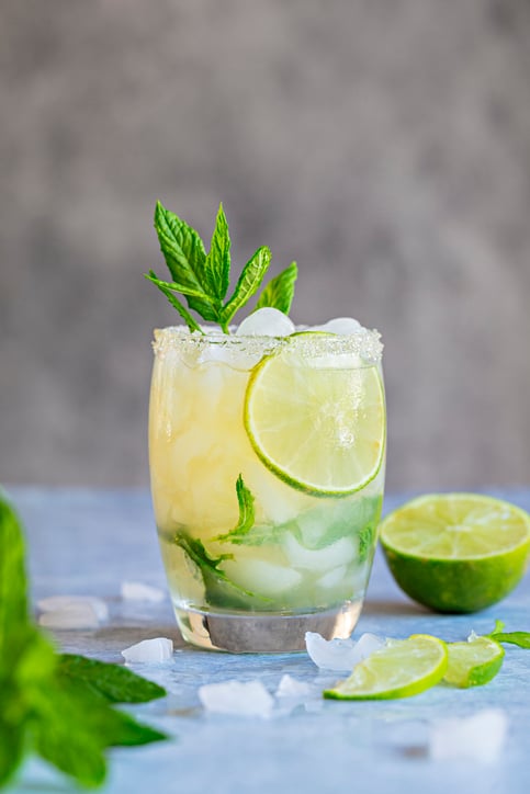 A fresh Mojito drink with mint leaves and lime and crushed ice. On a gray background.