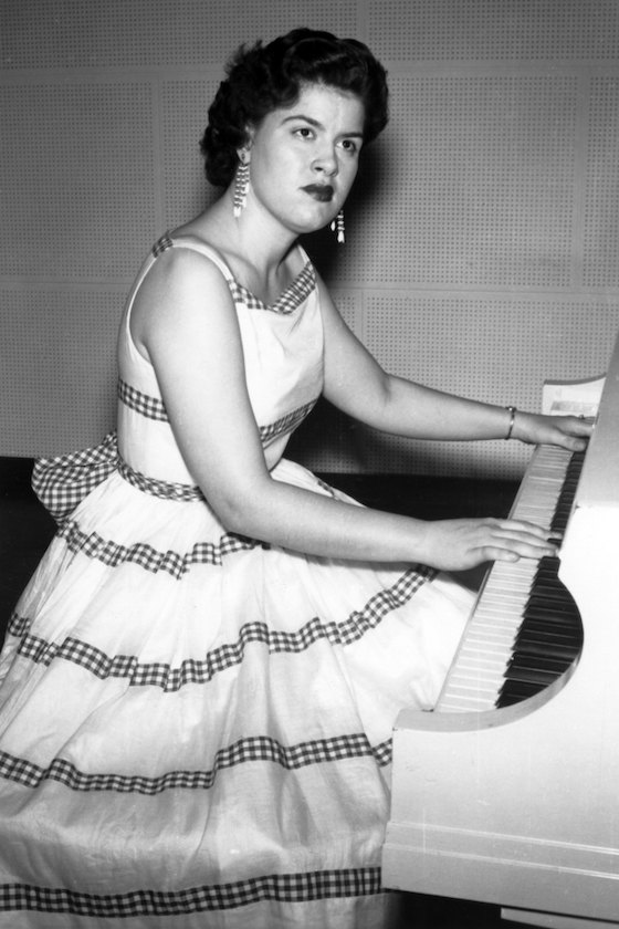 CIRCA 1957: Country musician Patsy Cline plays the piano wearing a dress in circa 1957. 