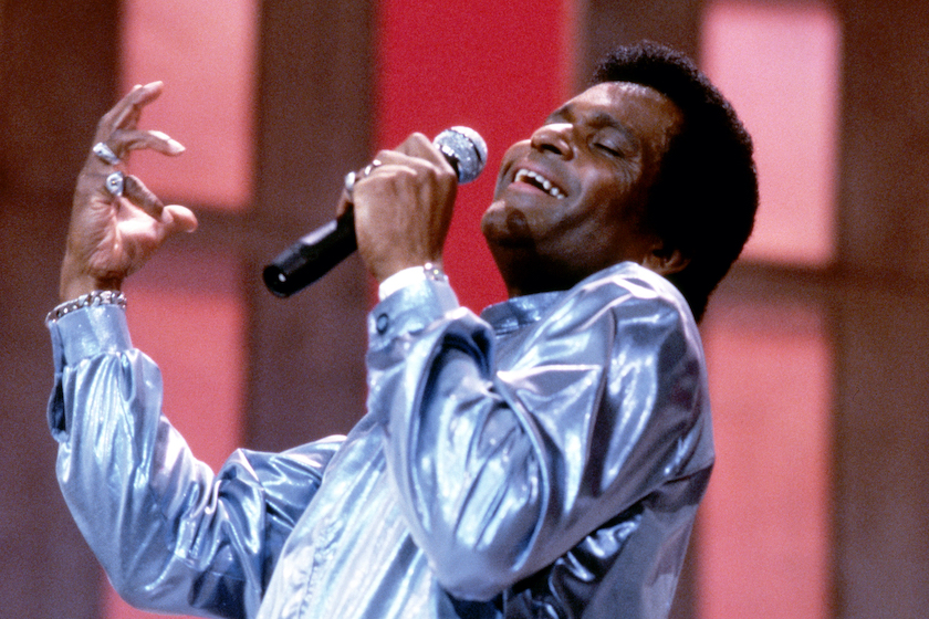 Charley Pride, US Country music singer, wearing a silver jacket and holding a microphone during a live concert performance, circa 1975.