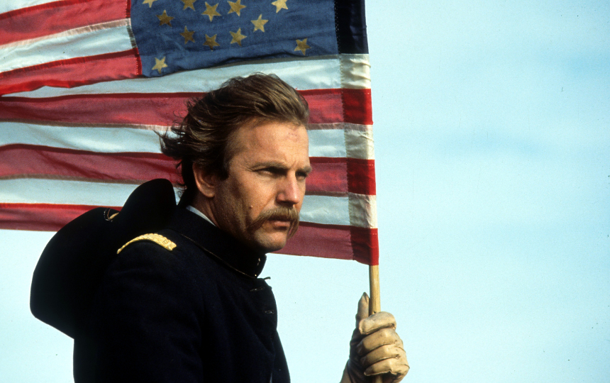 Kevin Costner holding an American flag in a scene from the film 'Dances With Wolves'