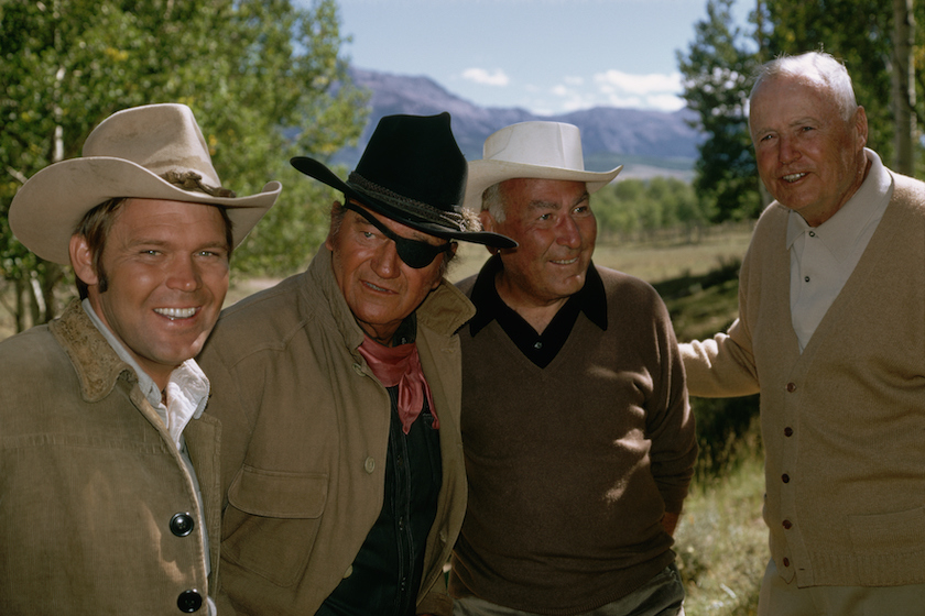 Glen Cambell (left) with John Wayne (in eyepatch) during the filming of True Grit in Colorado. Also on hand are (left to right) producer Hal Wallis and director Hal Hathaway. | Location: Near Ridgway, Colorado, USA.