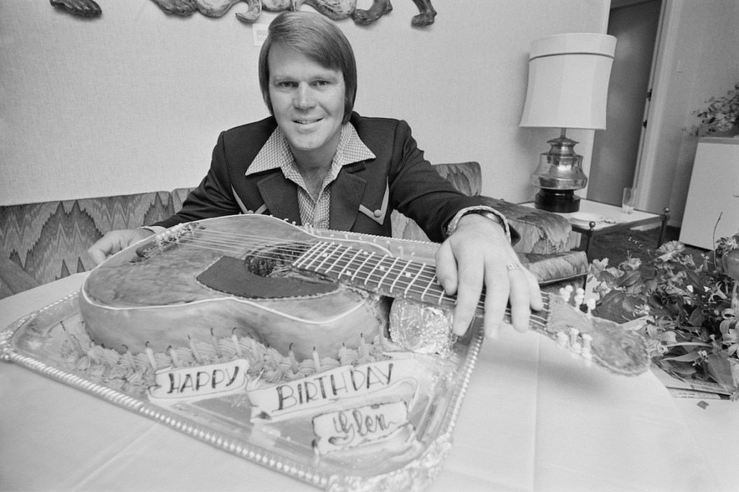 American singer, guitarist, songwriter, television host, and actor Glen Campbell (1936 - 2017) with his guitar-shaped birthday cake, UK, 25th April 1973.
