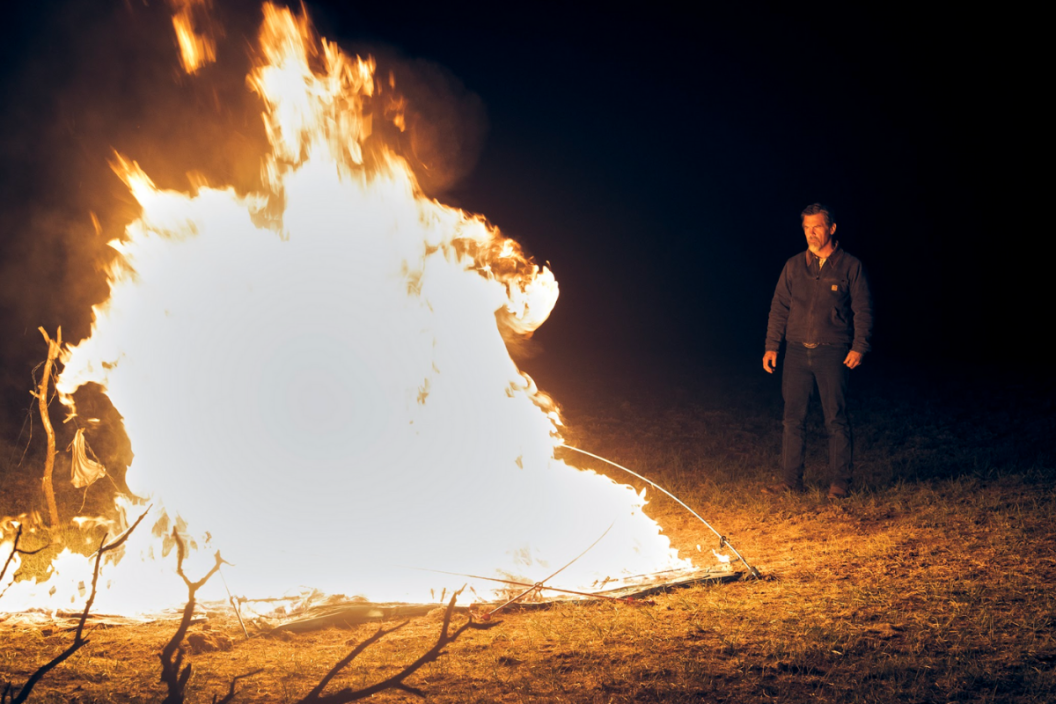 Josh Brolin as Royal Abbott stands in front of a large fire in a scene from 'Outer Range'
