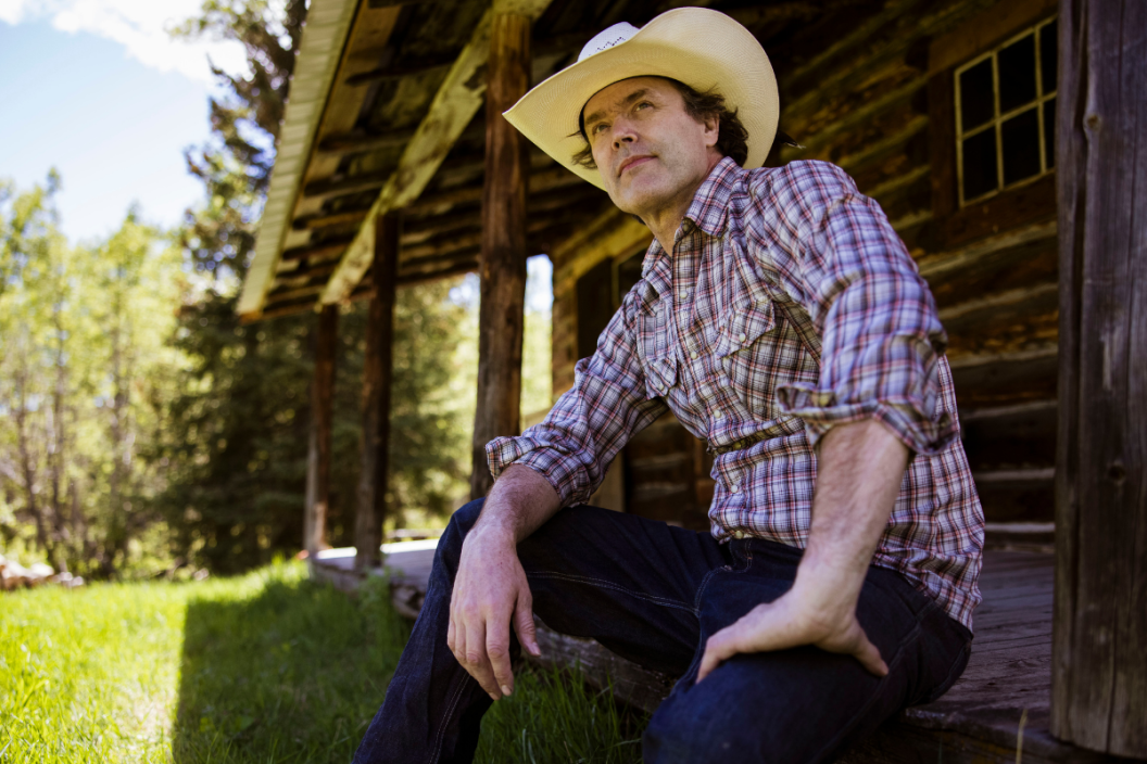 Corb Lund poses in front of cabin