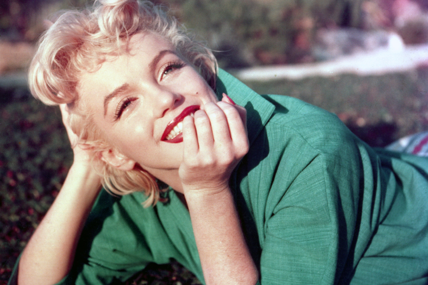Actress Marilyn Monroe poses for a portrait laying on the grass in 1954 in Palm Springs, California