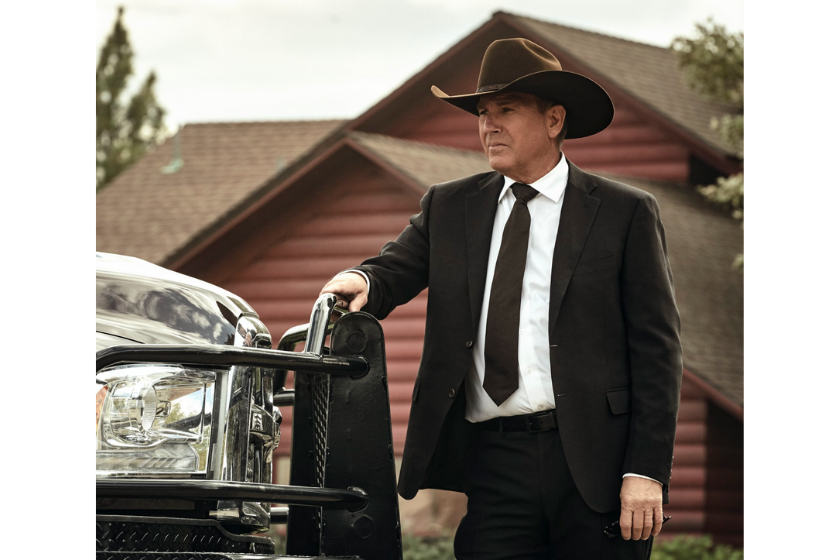Kevin Costner leaning against a car in a scene from 'Yellowstone'