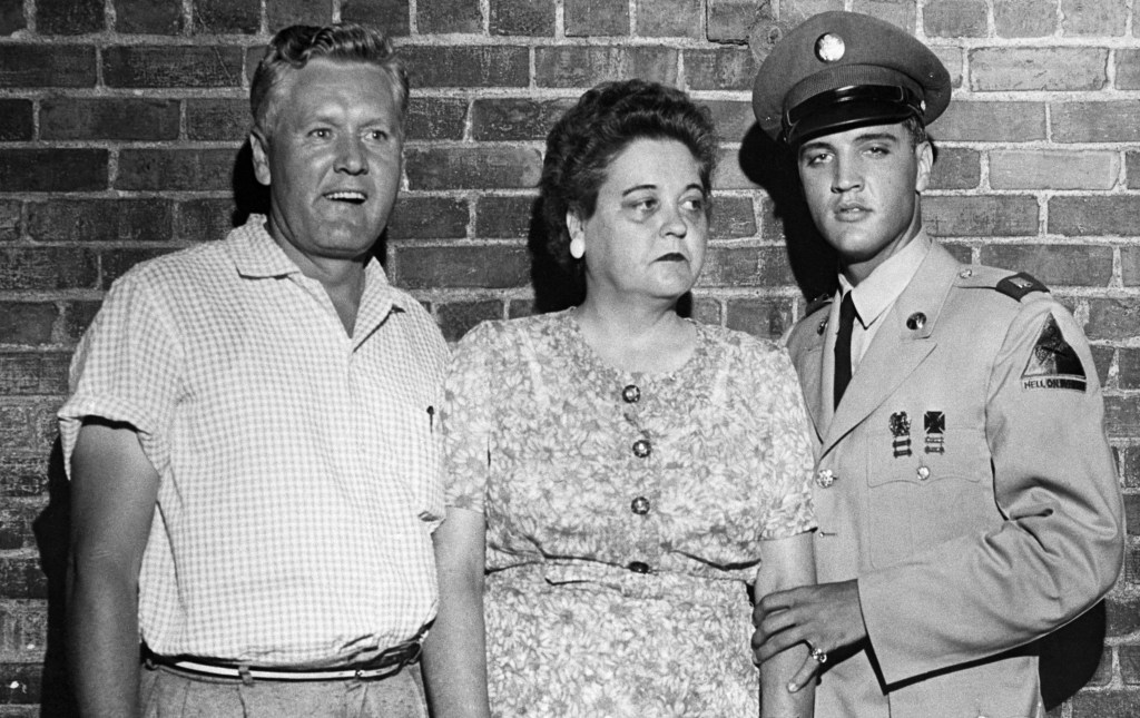 Memphis, Tennessee: Pfc. Elvis Presley, on his first leave from the Army, escorts his parents, Mr. and Mrs. Presley, from their mansion here to town for a sneak preview of the entertainer's latest movie, June 1st. The film is called "King Creole."