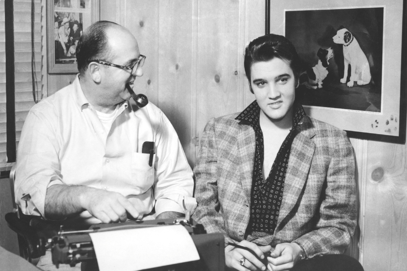 Singer Elvis Presley and his manager Colonel Tom Parker sit at a typewriter in front of the a picture of the RCA Victor Dog in circa 1956 in Memphis, Tennessee