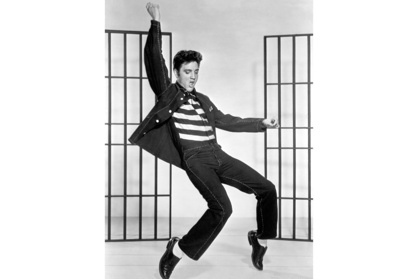 Elvis Presley (1935 - 1977) dancing in a stylized prison uniform in a promotional portrait for director Richard Thorpe's film, 'Jailhouse Rock.'