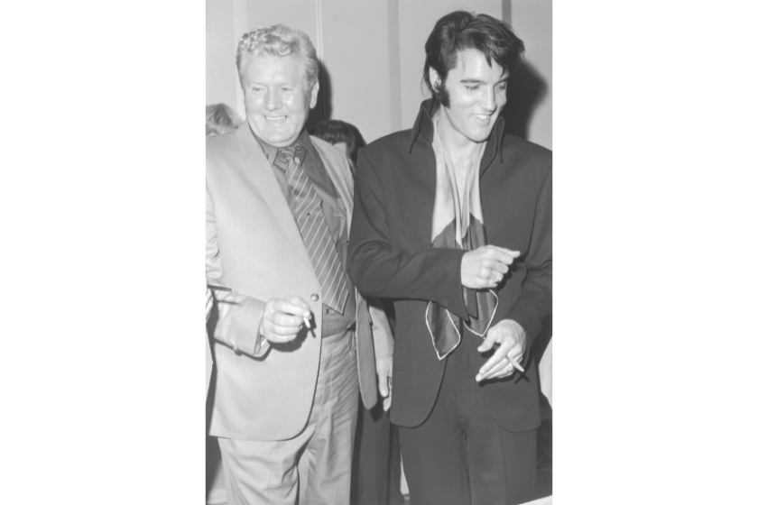 Elvis Presley (1935-1977) and his father, Vernon Presley (1916 - 1979), laugh while attending a party hosted by singer and actor Frank Sinatra for the opening of his daughter Nancy's nightclub act